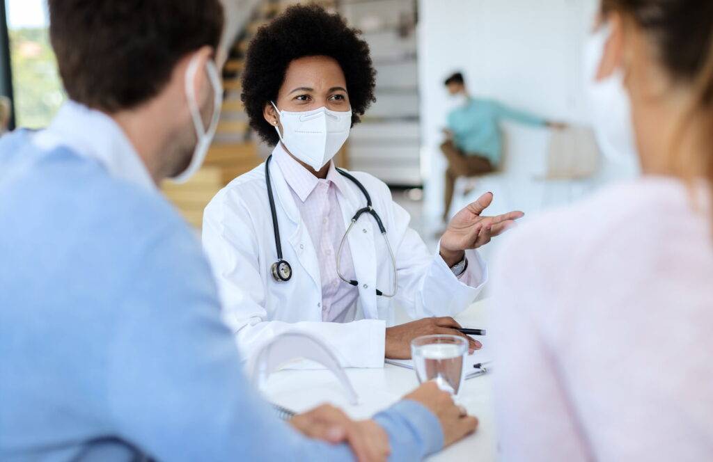 Médica explicando sobre o medicamento Tecentriq para um paciente e acompanhante.