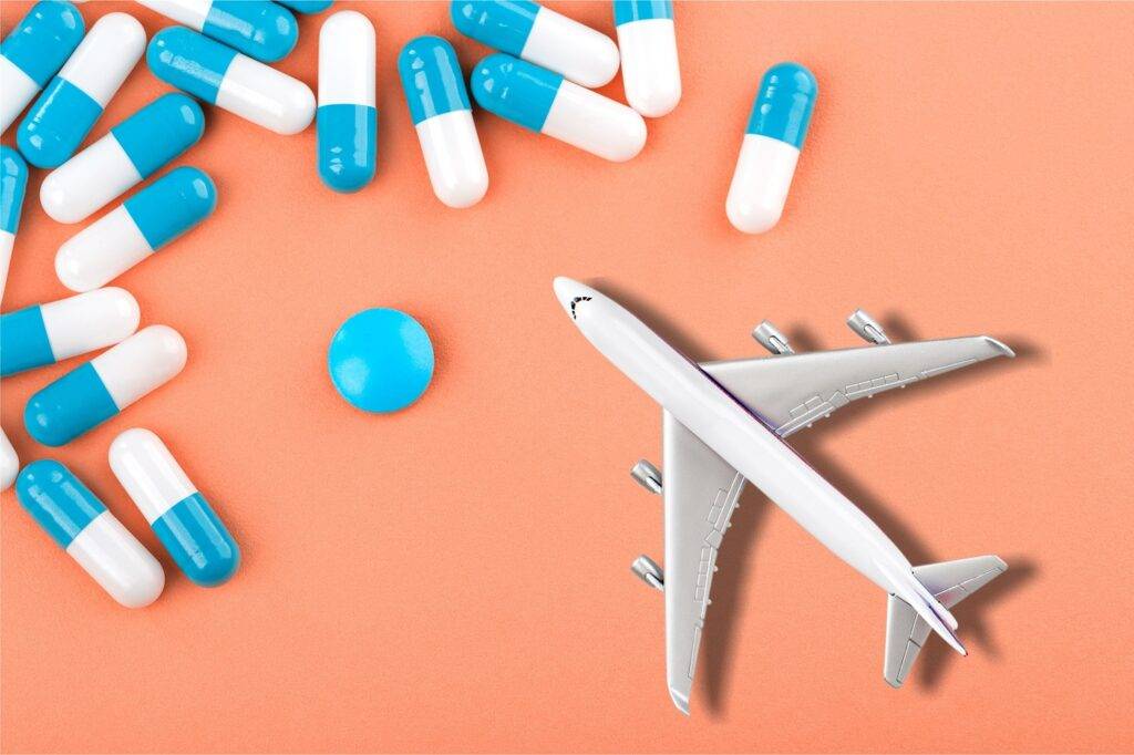 Imagem com medicamentos e avião em miniatura representando a assessoria de importação de medicamentos