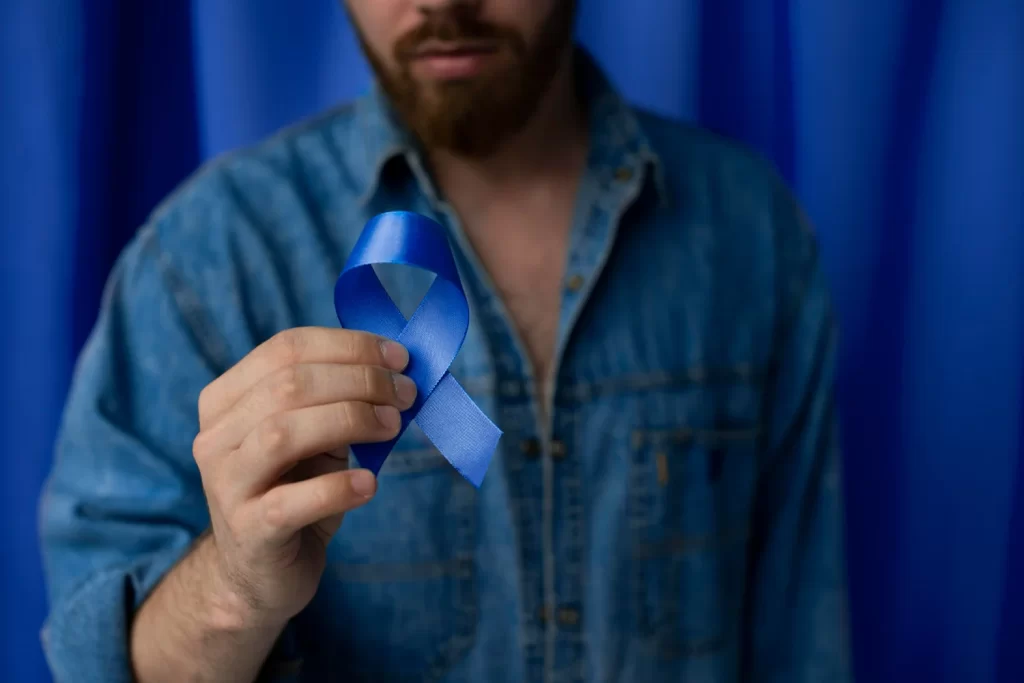Homem branco segurando faixa azul a favor do novembro azul, movimento que ajuda na prevenção do câncer de próstata