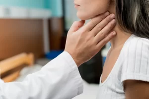 Mulher sendo examinada no pescoço, representando a investigação da doença de câncer no pescoço.