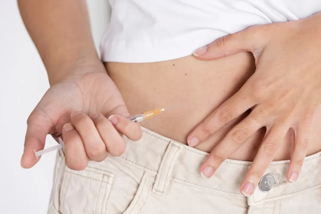 Paciente aplicando injeção do medicamento Adalimumabe, conhecido como Humira, na sua barriga.