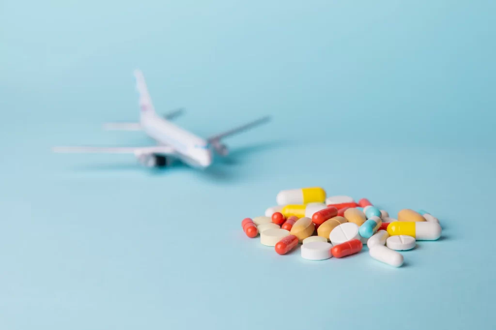 Imagem de um avião e diversas pílulas de remédio, simbolizando a importação de medicamentos por pessoa física.