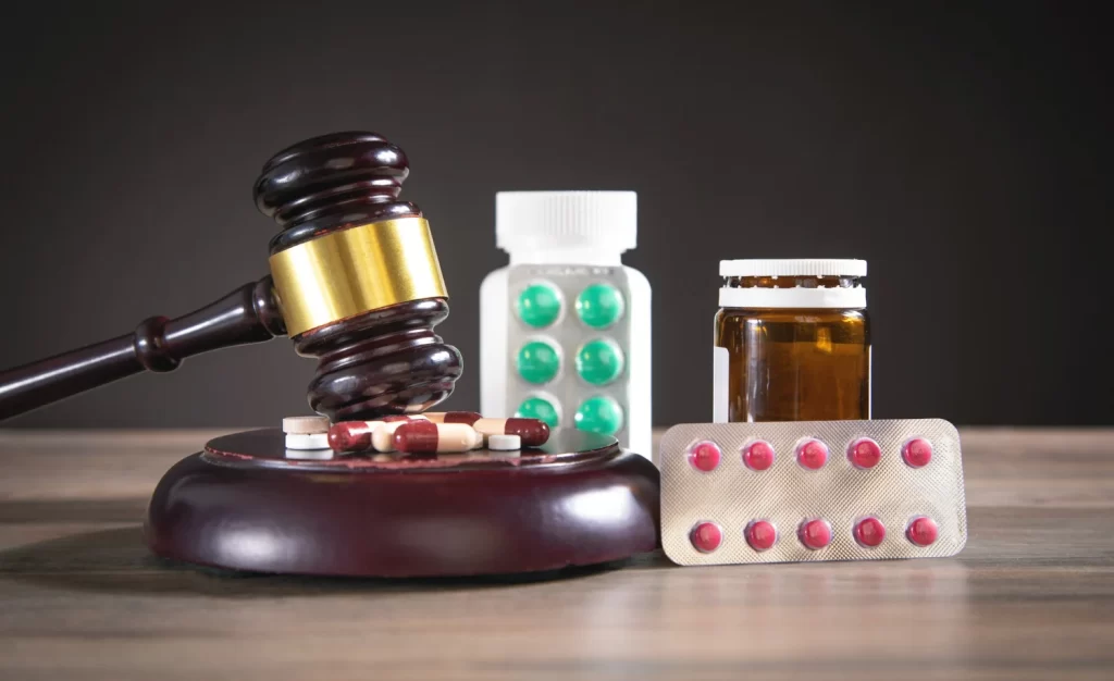 Martelo de juiz ao lado de remédios, ilustrando como entrar na justiça para conseguir medicamento de alto custo