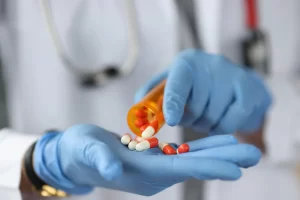 Médico com luvas azuis segura pílulas, ilustrando a diferença entre medicamento manipulado e industrializado