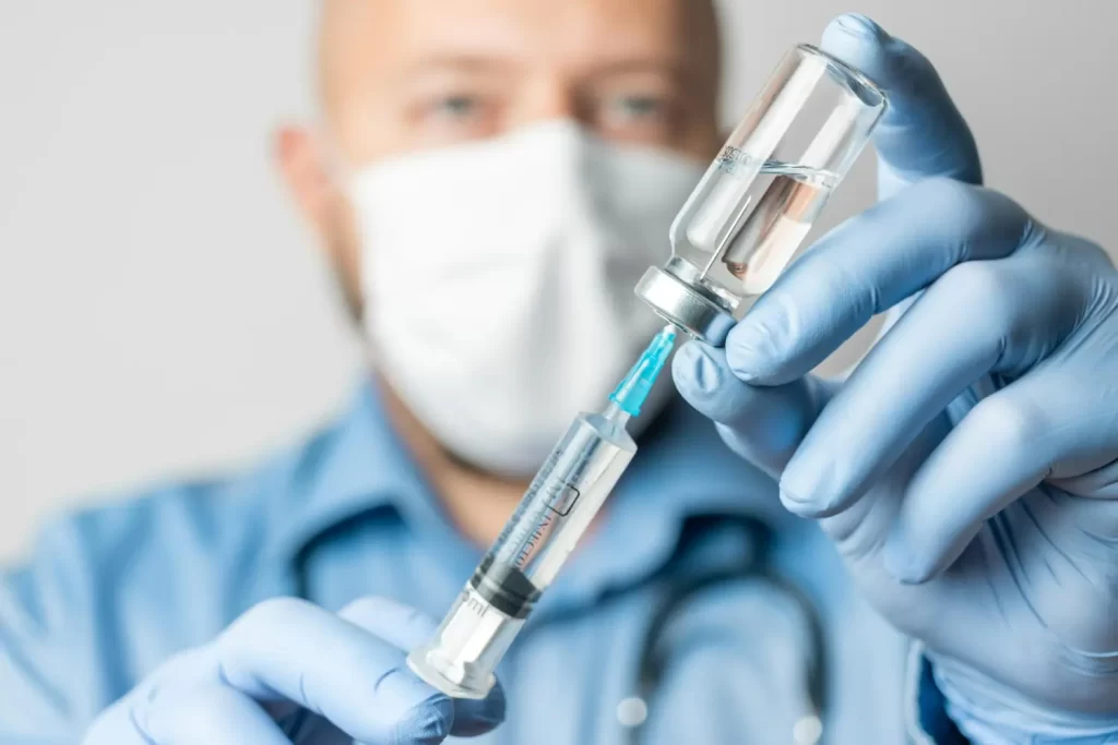 Médico de luvas segura uma seringa e um frasco de medicamento, ilustrando para que serve o remicade