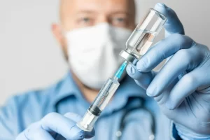 Médico de luvas segura uma seringa e um frasco de medicamento, ilustrando para que serve o remicade