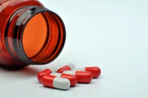 Cápsulas e frasco aberto, ilustrando os riscos de medicamentos falsificados