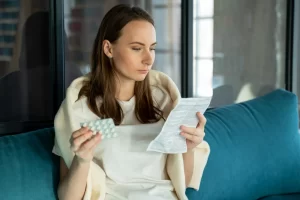 Jovem segura cartela de pílulas e lê bula de remédio para identificar medicamento falsificado