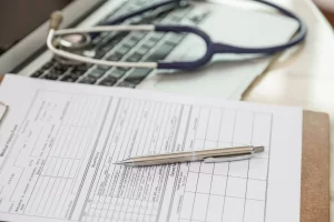 Estetoscópio ao lado de uma prancheta com histórico médico e documentos para tratamento oncológico