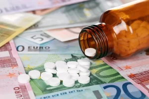 Frasco de medicamento com comprimidos sobre notas de euro, ilustrando quanto custa importar um medicamento