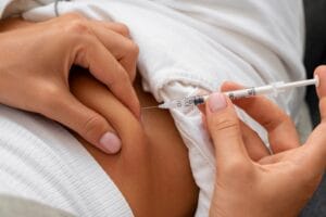 Profissional aplicando injeção de tratamento com humira em paciente deitada