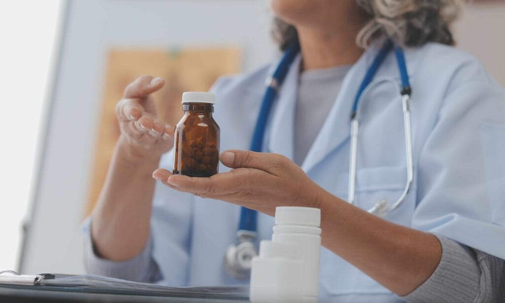 Médica segura frasco de medicamento durante explicação sobre uso compassivo de medicamentos.