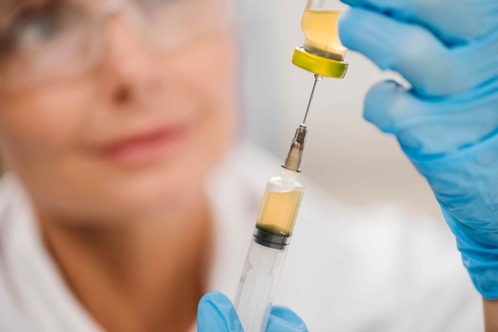 Médica com seringa e frasco de medicamento inibidor de tirosina quinase